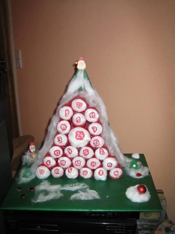Ein selbstgemachter Adventskalender aus roten, nummerierten Rollen, in Pyramidenform arrangiert, steht auf einem Tisch.