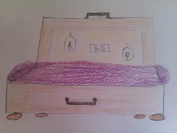 Ein Holzkoffer dient als Bett, ausgelegt mit einer lila Decke; an der Rückseite hängen Bilderrahmen mit Bäumen und einem Vogel.