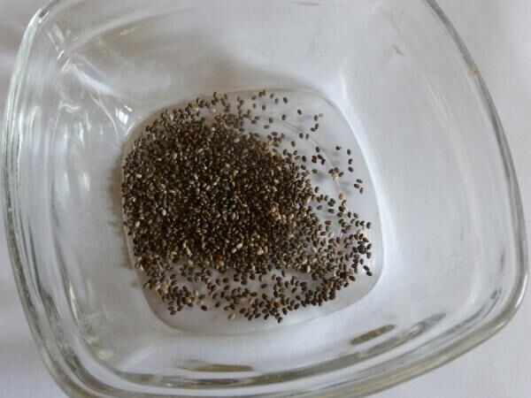 Chia-Samen liegen in einer durchsichtigen Glasschale, auf einer weißen Oberfläche, bereit als gesunder Ei-Ersatz.