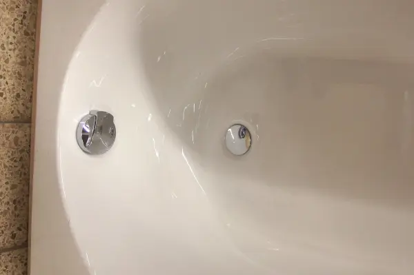 In einer Duschwanne sind zwei Abflussöffnungen sichtbar, während Wasser stagniert, was auf einen verstopften Abfluss hindeutet.