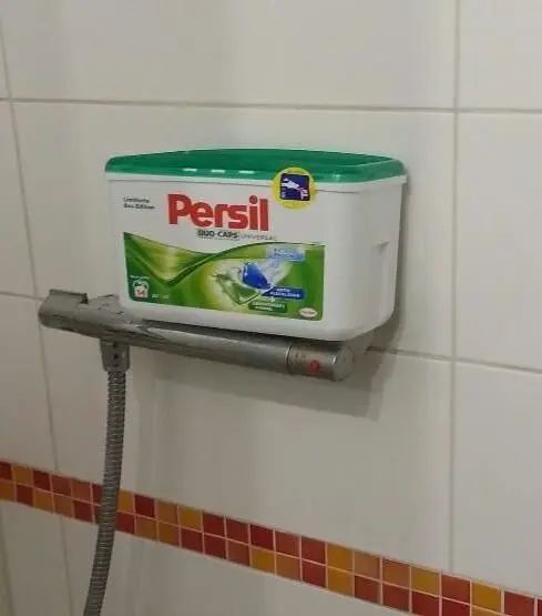Eine Seifenbox hängt an einer Fliesenwand in der Dusche und bietet Reinigungsmittel für die Dusche an.