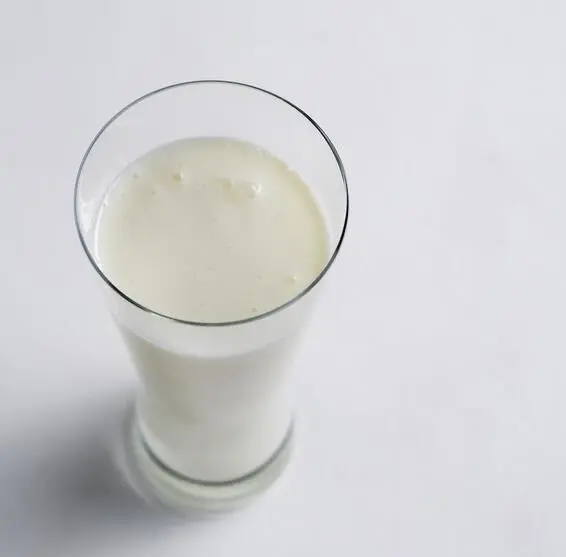 Ein Glas kalorienarmer Ayran aus Buttermilch steht auf einem hellen Tisch, bereit zum Trinken.