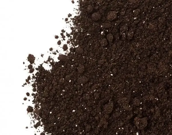 Blumenerde liegt verstreut auf einem weißen Hintergrund und zeigt ihre dunkle, krümelige Textur, ideal zum Weiterverwenden.