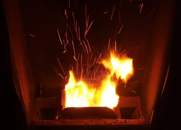 Ein offenes Kaminfeuer lodert und sprüht Funken, während die Wärme den Raum beleuchtet und eine gemütliche Atmosphäre schafft.