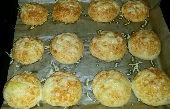 Käsebrötchen liegen frisch gebacken auf einem Blech, goldbraun und knusprig, bereit zum Servieren.