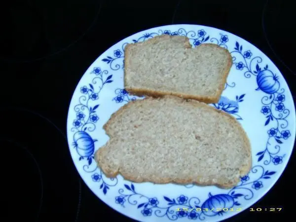 Zwei Scheiben Molkebrot liegen auf einem weißen, blau gemusterten Teller auf einem dunklen Untergrund; Datum: 15.03.2012 10:27.