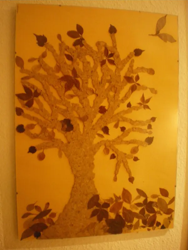 Ein Baum ist aus bunten Blättern gestaltet, umgeben von weiteren Blättern auf einem hellen Hintergrund.
