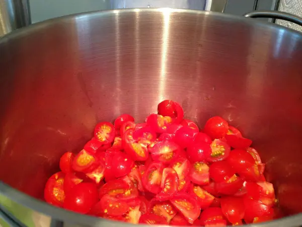 Frische, geschnittene Tomaten liegen in einem großen Edelstahltopf, bereit zur Zubereitung des veganen Chutneys.
