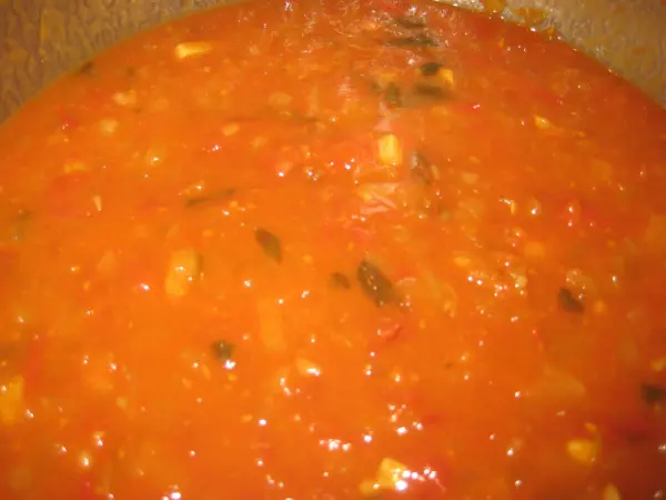Ein dickflüssiges Tomaten-Chutney köchelt in einem Topf, bereit, über Spaghetti serviert zu werden, ist vegan und lecker.