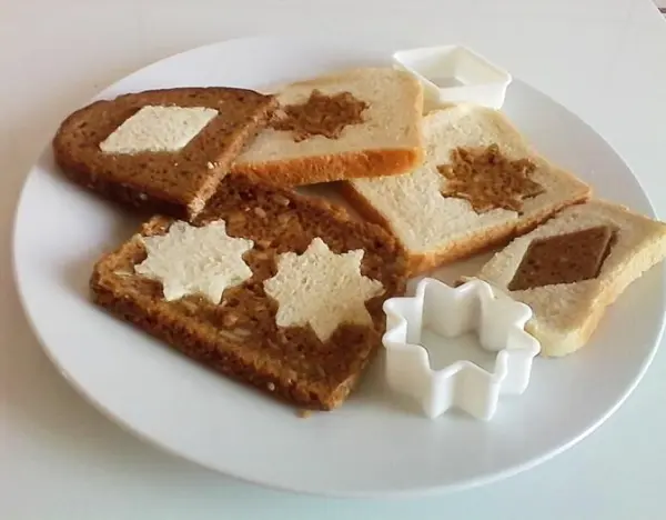 Bunte Brotscheiben liegen auf einem Teller, dekorativ angeordnet mit verschiedenen, essbaren Mustern und Formen.