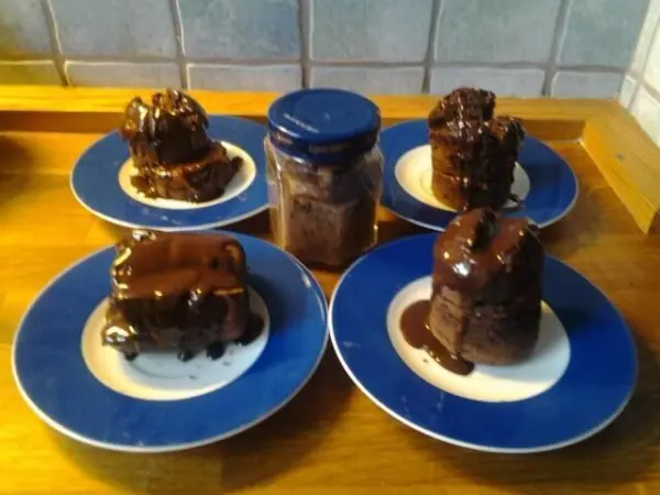 Ein glutenfreier Apfel-Mandelkuchen steht auf blauen Tellern, umgeben von einem Glas köstlicher Schokoladensauce.
