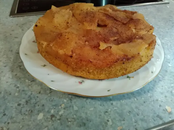 Ein glutenfreier Apfel-Mandelkuchen ruht auf einem weißen Teller, umgeben von einer hellen Küchentheke.
