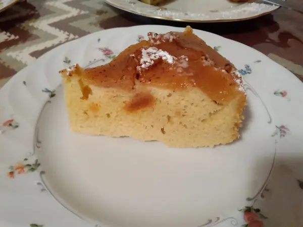 Ein Stück glutenfreier Apfel-Mandelkuchen liegt auf einem dekorativen Teller und zeigt eine goldene, saftige Oberfläche.