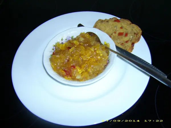 Ein Schälchen Kürbis-Chutney steht auf einem weißen Teller, daneben liegt ein Stück Brot. Chutney wird serviert.