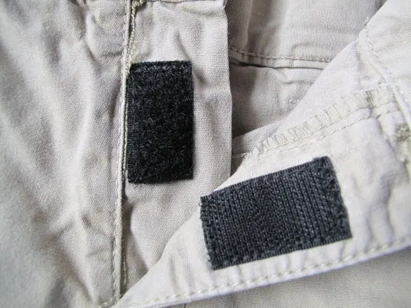 Zwei schwarze Klettbandstücke sind an der Öffnung einer Kinderhose angebracht, um den kaputten Reißverschluss zu ersetzen.