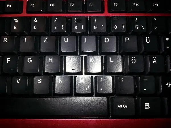 Eine verklebte PC-Tastatur mit hervorgehobenen Tasten zeigt Schmutz und Ablagerungen, die dringend gereinigt werden müssen.