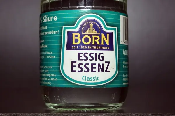 Ein Glas-Essigessenz steht auf einem dunklen Hintergrund, bereit zur Anwendung gegen Marderschäden in Fahrzeugen.