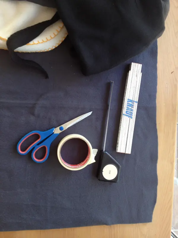 Ein paar Scheren, Klebeband und ein Maßband liegen auf einem Tisch, um ein Kissen für Hund und Katze ohne Nähen zu erstellen.