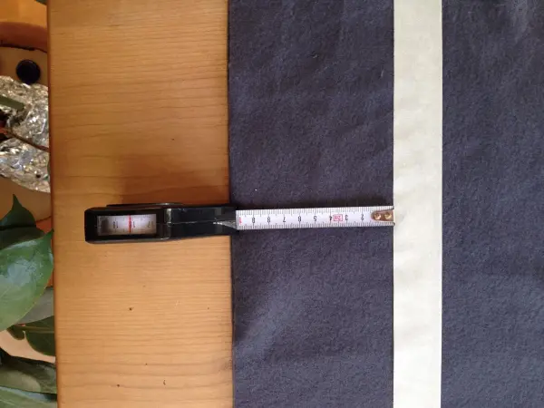 Ein Maßband liegt auf einem dunklen, gefalteten Stoff, während es zur Vorbereitung eines Kissen für Hund und Katze benutzt wird.