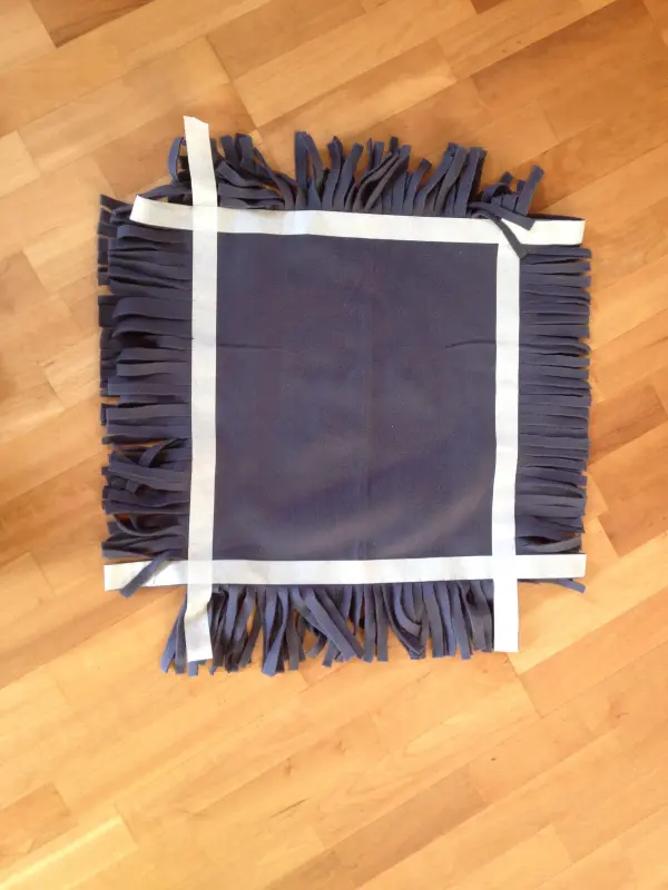 Ein Kissen aus Stoffquellen liegt auf einem Holzboden, bereit für Hunde und Katzen, ohne Nähen gestaltet.