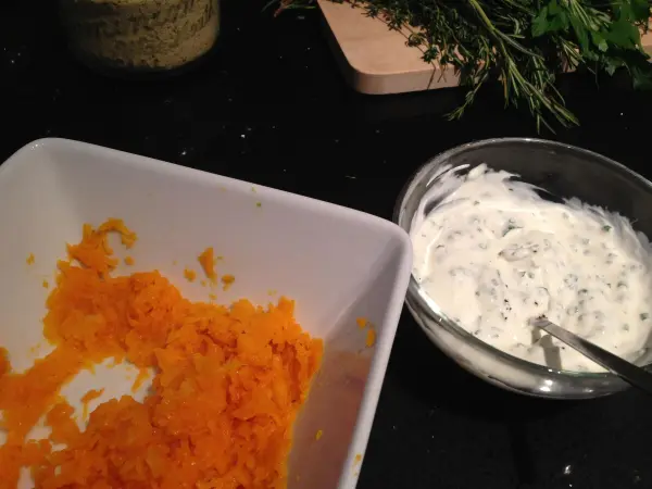 Gehackter, orangefarbener Butternut-Kürbis liegt neben einer cremigen, weißen Kürbis-Kräutercreme in einer Küche.