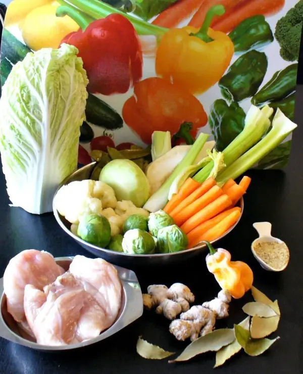 Ein bunter Teller mit frischem Gemüse und Hähnchenfleisch wird vorbereitet, um eine gesunde Schlanksuppe zu kreieren.
