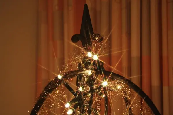 Ein funkelnder alternativer Weihnachtsbaum mit Lichtern steht im Innenraum vor einem Vorhang mit sanften Farben.