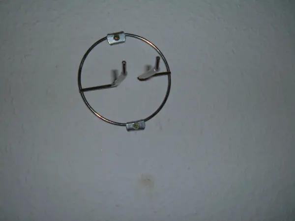 Ein Wandhalter aus Metall zur Aufhängung einer Gitarre ist an einer neutralen Wand montiert.