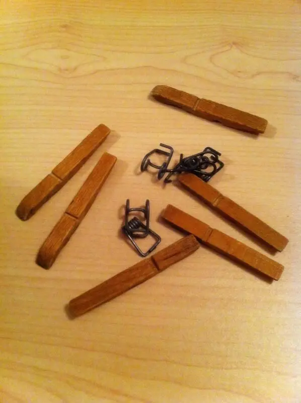 Ein Stern aus alten Wäscheklammern liegt auf einem hellen Holzuntergrund, bereit, für die Weihnachtsdeko verwendet zu werden.