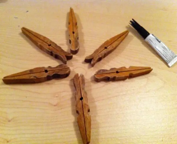 Ein Stern aus alten Wäscheklammern liegt auf einem Tisch, umgeben von Bastelmaterialien für die Weihnachtsdeko.