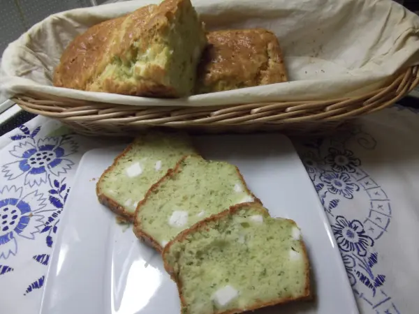 Feta-Kuchen mit Kräutern liegt in einem Korb, während geschnittene Stücke auf einem Teller serviert werden.