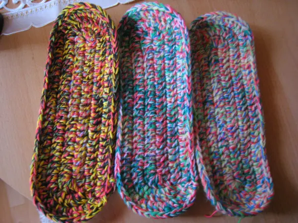 Dicke Socken sind in bunten Farben gestrickt und liegen nebeneinander auf einem Tisch, bereit zum Tragen als Hausschuhe.