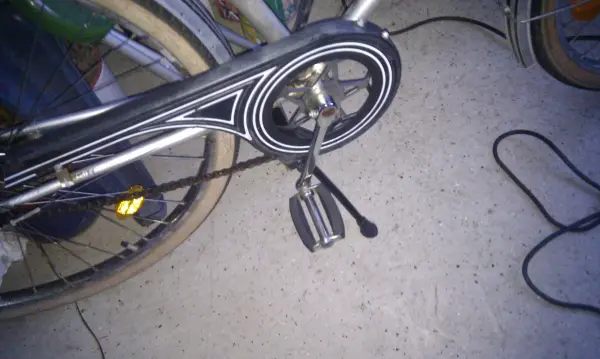 Ein Fahrrad mit einem rostigen Kettenblatt steht in einer Garage, während jemand versucht, den Rost zu entfernen.