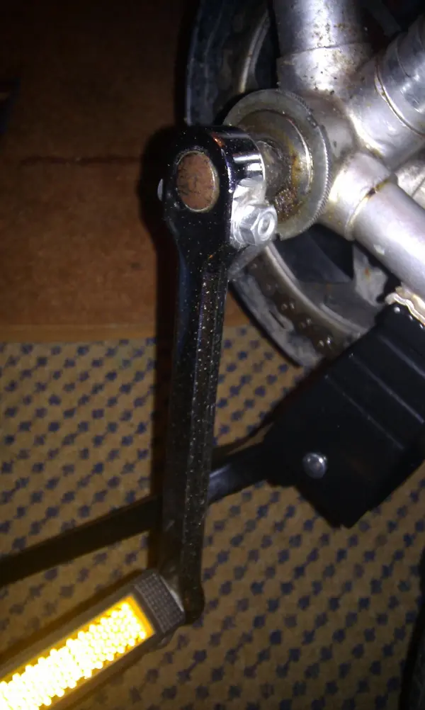 Ein Fahrradpedal wird in einer Werkstatt überprüft, um Rost am Fahrrad zu entfernen. Der Hintergrund ist ein Teppichboden.