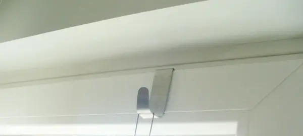 Ein Halter für eine Fensterdekoration ist am oberen Fensterrahmen montiert, ohne den Rahmen zu beschädigen.