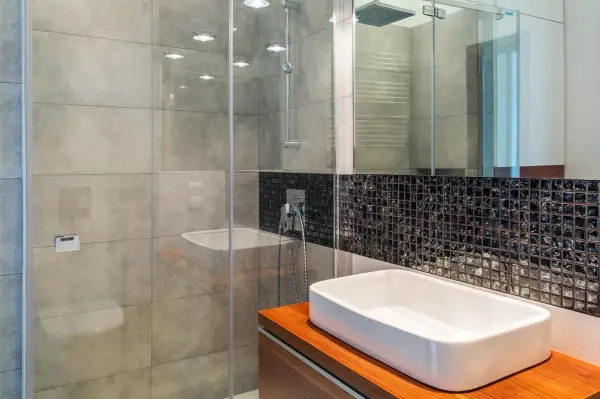 Ein modernes Badezimmer mit einer Glasduschtür, die in einem eleganten Ambiente steht, ideal zum Entfernen von Kalk.