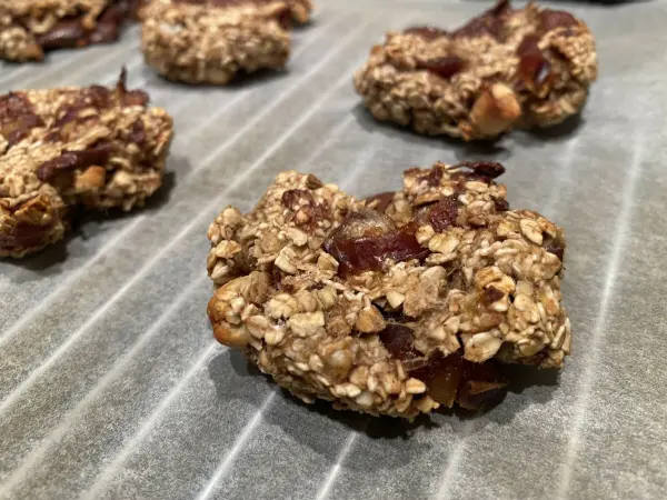 Haferflocken-Bananen-Kekse liegen frisch gebacken auf Backpapier, bereit zum Genießen. Gesund und vegan, ideal für Snacks.