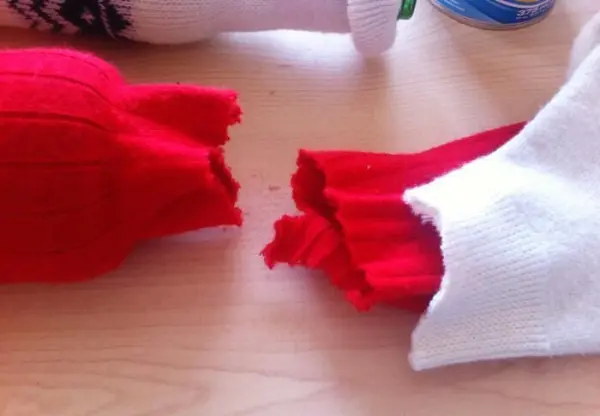 Rot- und weiße gestrickte Überzüge umhüllen Vasen und Flaschen und verleihen einen winterlichen Charme auf einem Holztisch.
