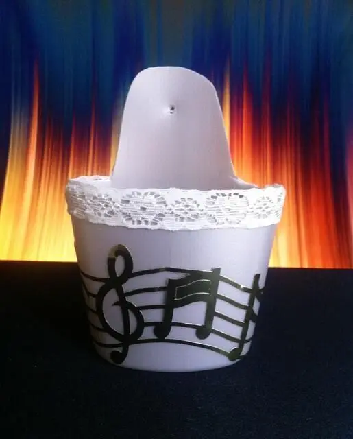 Ein blühender Blumenbehälter hängt dekorativ mit Musiksymbolen vor einem farbenfrohen, lebhaften Hintergrund.