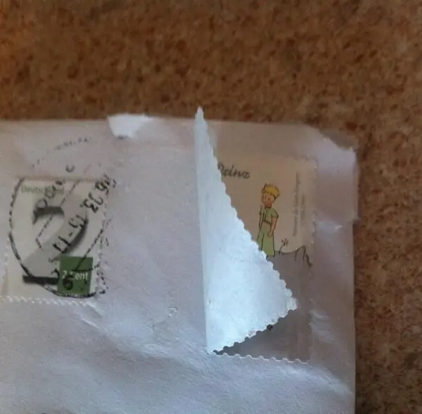 Ein Umschlag mit teilweise abgelösten Briefmarken liegt auf einer flachen Oberfläche, bereit für das Ablösen der Marken.