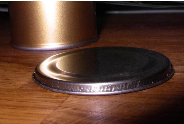 Eine Metall-Dose liegt auf einem Holzuntergrund, während der Deckel sanft auf der Seite ruht, bereit zum Öffnen.