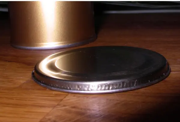 Eine Metall-Dose liegt auf einem Holzuntergrund, während der Deckel sanft auf der Seite ruht, bereit zum Öffnen.