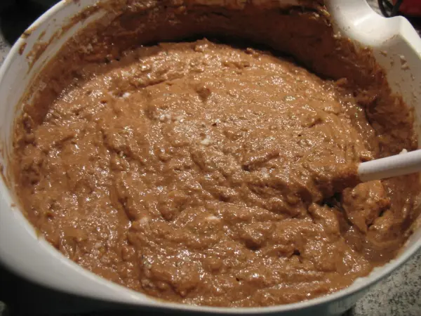 Lockere Brownie-Teigmischung in einer Schüssel wird mit einem Löffel gemischt. Der Teig sieht cremig und schokoladig aus.