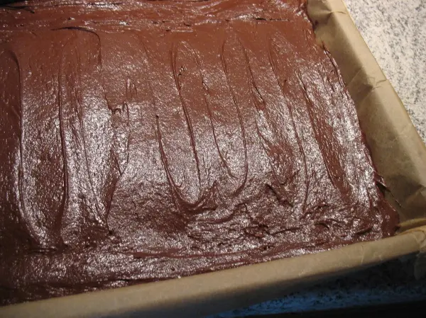 Lockere Brownies ruhen in einer Backform, bereit zum Backen in einer freundlichen Küchenszene.