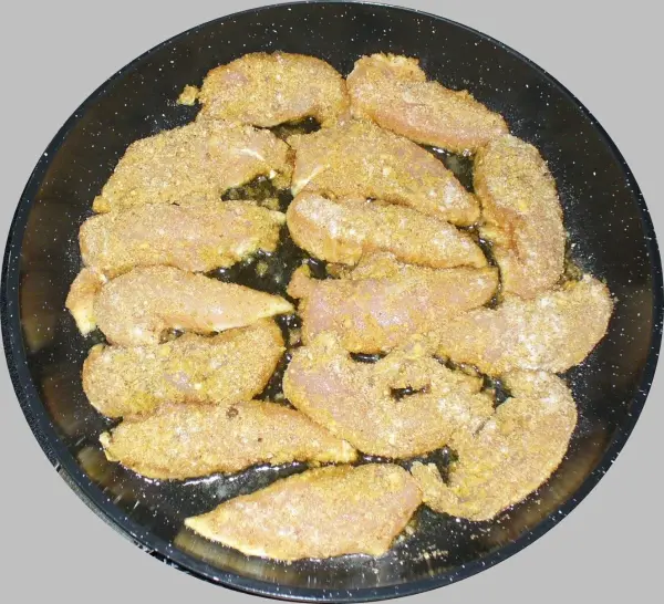 Zarte Hähnchenschnitzel liegen auf einem schwarzen Teller und sind mit einer knusprigen Panade bedeckt.