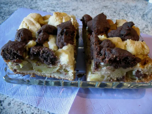 Apfelkuchen mit Dinkelmehl liegt auf einer Platte, die marmorierten Streusel sind goldbraun und appetitlich.