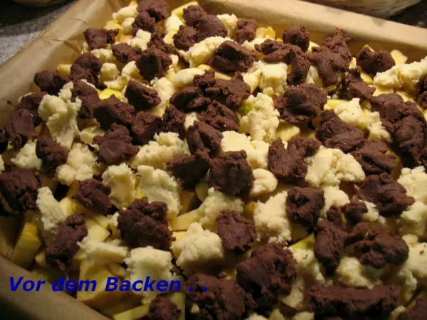 Ein Blech Apfelkuchen mit Dinkelmehl ist mit marmorierten Streuseln bedeckt und wartet darauf, gebacken zu werden.