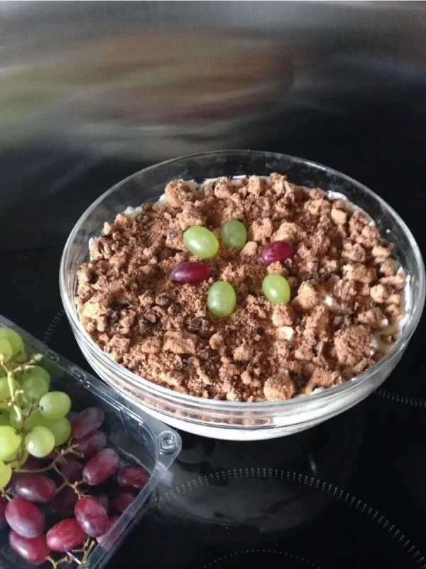 Cookies mit Weintrauben sind in einer Schüssel. Sie liegen auf einer glatten Oberfläche, daneben frische Weintrauben.