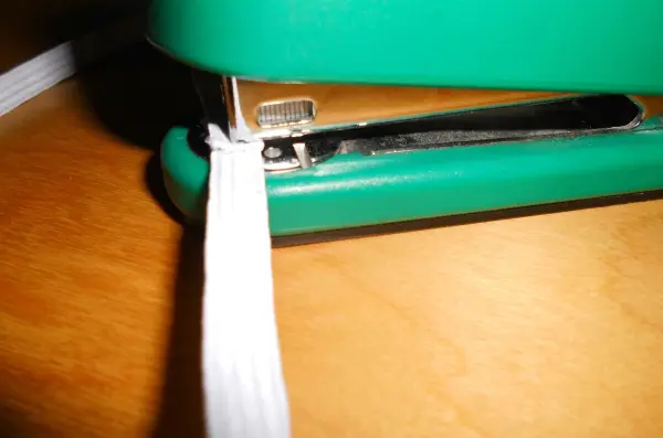 Ein grüner Tacker befestigt ein Lesebändchen aus Stoff auf einem Tisch, um persönliche Lesebändchen zu erstellen.
