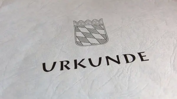 Eine Urkunde mit einer Wappenzeichnung, die den Erwerb einer denkmalgeschützten Wohnung dokumentiert.